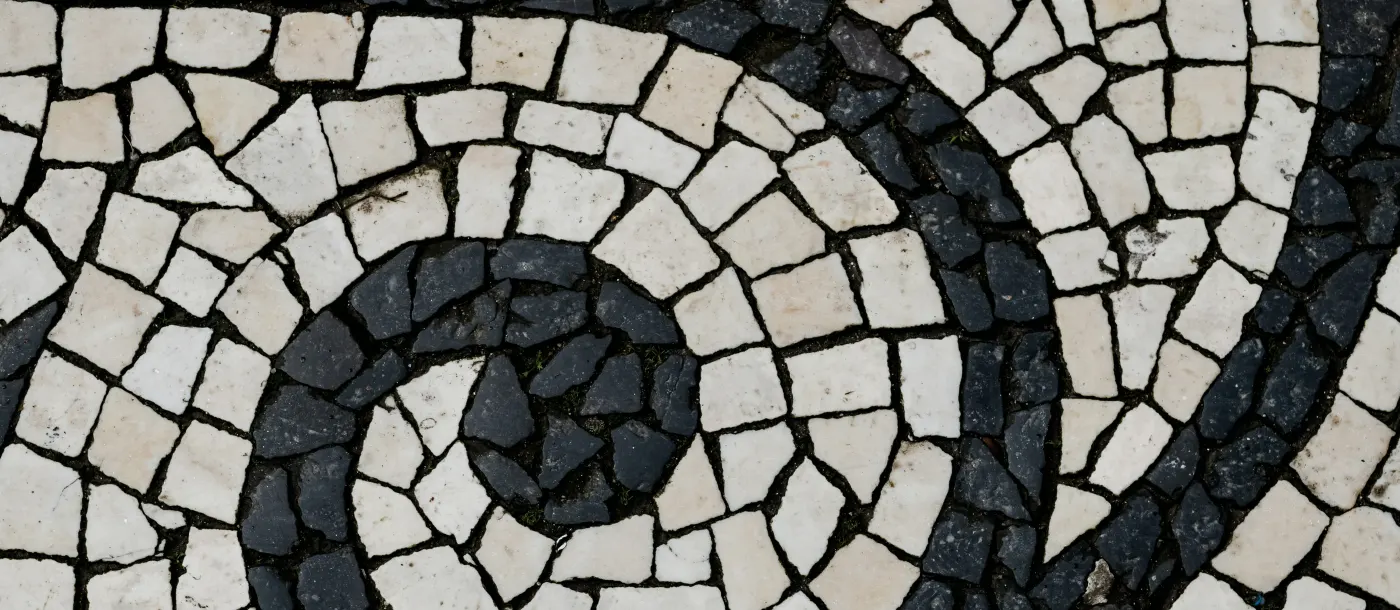 Traditional Portuguese calçada paving — hand-cut white limestone and dark basalt set in a spiral.