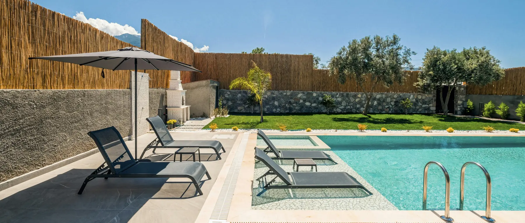 A wide expanse of pale limestone terrace paving in hard midday sun, with crisp shadows and a swimming pool alongside.